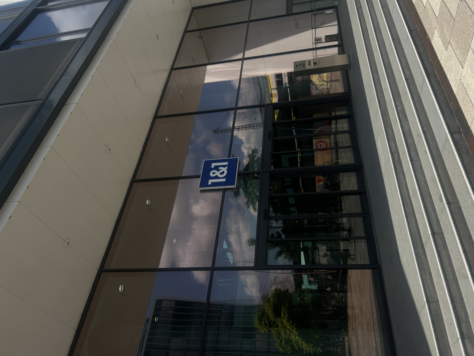 Glass façade with a blue 1&1 logo — a 1&1 site in Germany, seen from the street.